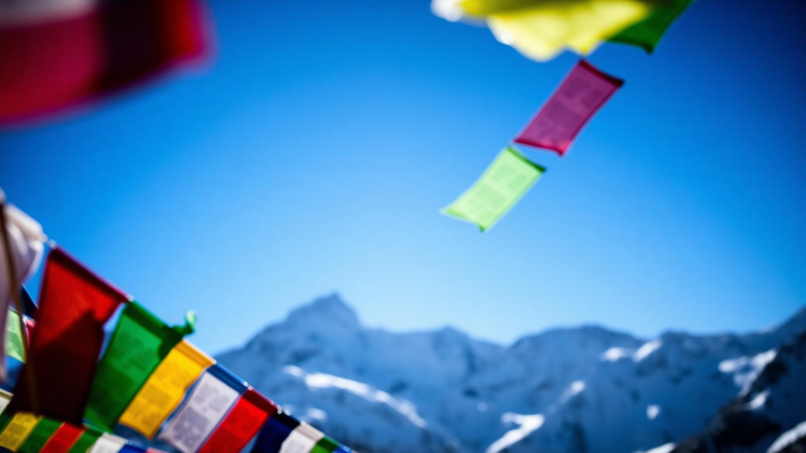Gebetsfahnen vor schneebedeckten Himalaya-Gipfeln